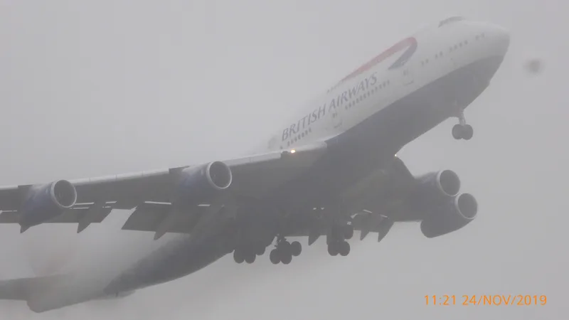 Boeing 747 British Airways en décollage de Heathrow (piste 27L) dans un brouillard dense — visibilité très réduite, l'avion disparaît dans la brume